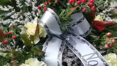 Smuteční věnec s bílými růžemi a stříbrnou stuhou s černým nápisem.