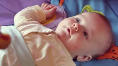 Miminko leží na barevné hrací podložce ve věku dvou měsíců.