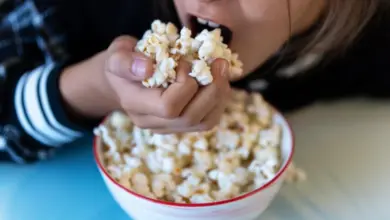 Dětské dítě snímá popcorn z misky.