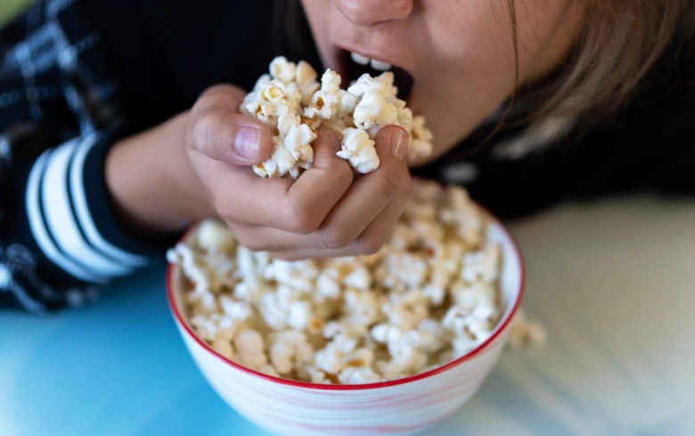 Dětské dítě snímá popcorn z misky.