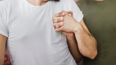 Dva muži se drží za ruce před cihlovou zdí.