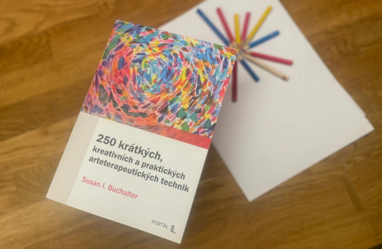 Kniha o technice arteterapie s barevnými tužkami na dřevě.