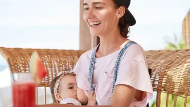 Žena kojí své dítě venku u stolu.