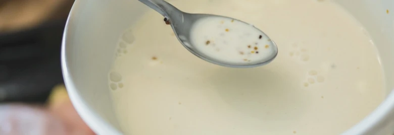 Bílá zakysaná smetana v misce s lžící.