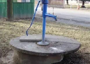 Modrá ruční čerpadlo studně venku na betonu.