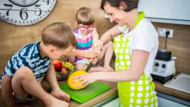 Matka krájí ovoce s dětmi v kuchyni.