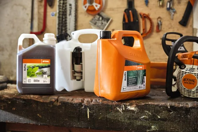 Nádrže na palivo značky STIHL a řetězová pila v dílně.