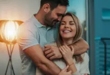 Muž objímá ženu s úsměvem v útulném interiéru.