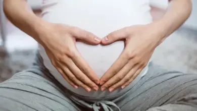 Těhotná žena drží ruce na břiše v tvaru srdce.