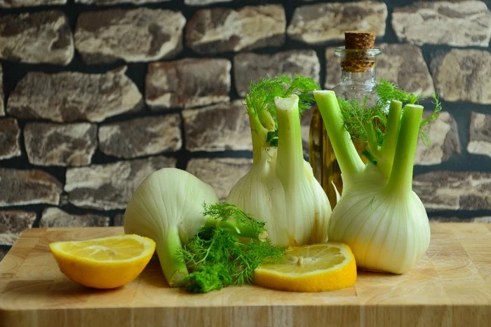 Čerstvé hlavičky fenýku s citronem na dřevěném prknu.