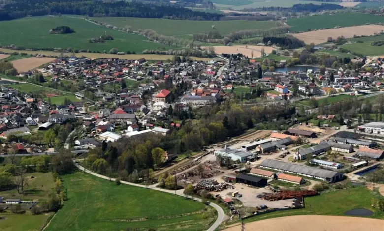 Pohled z letadla na vesnici s poli a lesy v okolí.