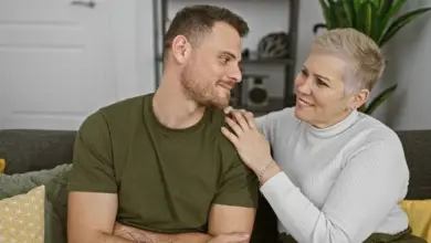 Mladý muž a starší žena se usmívají na pohovce.
