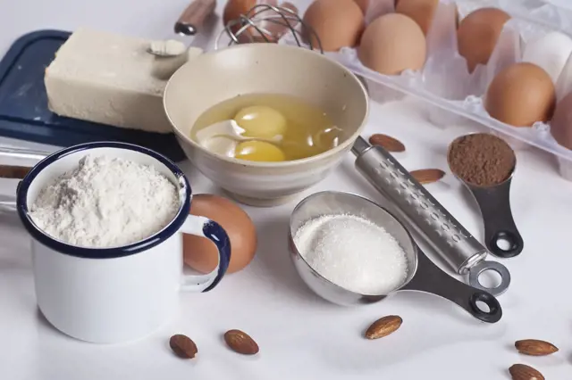 Suroviny na pečení s měřicími lžičkami a šálkem mouky.