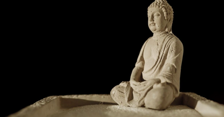 Socha Buddhy v meditaci na tmavém pozadí.