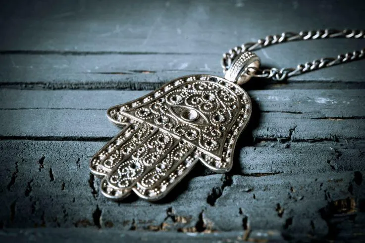 Stříbrný talisman ruka Fatimy s detailním řezbářstvím na dřevě.