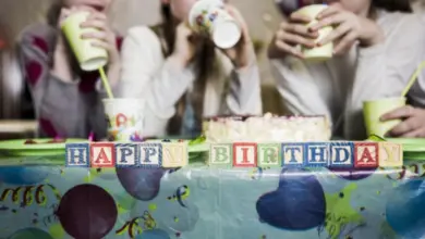 Dívky oslavují narozeniny s dortem a nápisem Happy Birthday na stole.