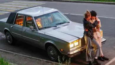 Muž a žena se objímají vedle starého vozu na silnici.