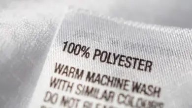 Bílá etiketa s nápisem 100 % polyester na textilu.
