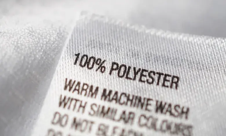 Bílá etiketa s nápisem 100 % polyester na textilu.