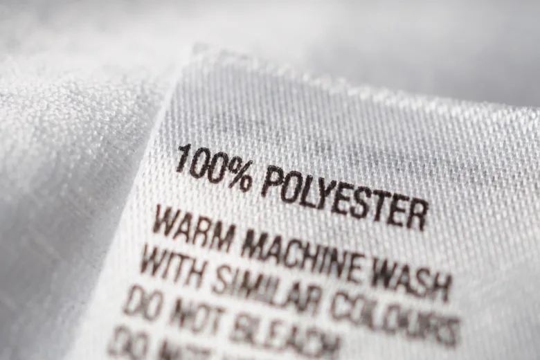 Bílá etiketa s nápisem 100 % polyester na textilu.