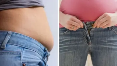 Žaludek se nafukuje, žena si upravuje kalhoty kvůli břišnímu tlaku.