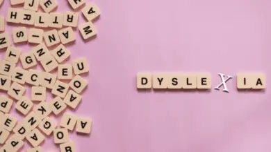 Slovo dyslexie napsané dřevěnými písmenky na růžovém pozadí.