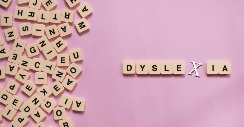 Slovo dyslexie napsané dřevěnými písmenky na růžovém pozadí.
