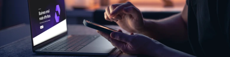 Osoba pracuje na e-mailu pomocí notebooku a chytrého telefonu.
