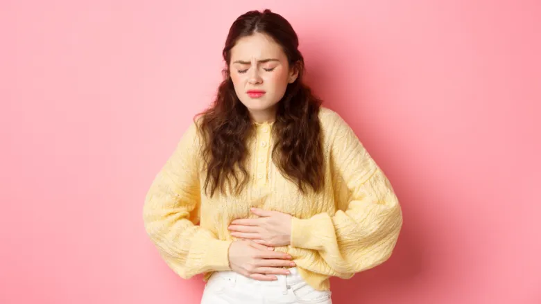 Dívka drží břicho v bolesti při menstruačních křečích.