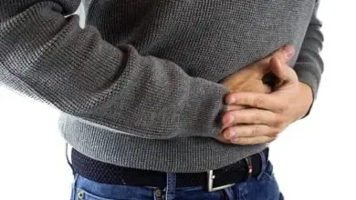 Muž drží břicho v bolesti po jídle hroznů.