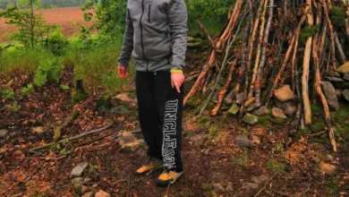 Chlapec stojí v lese u stromu s větvemi.