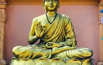 Zlatá socha Buddhy sedící v meditaci na lotosu.