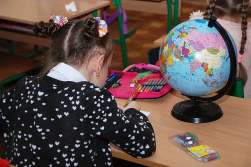 Dívka kreslí u globusu v učebně - příklad vzdělávacího prostředí.