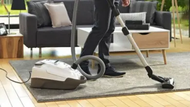 Osoba vysává koberec v obývacím pokoji s vysavačem.