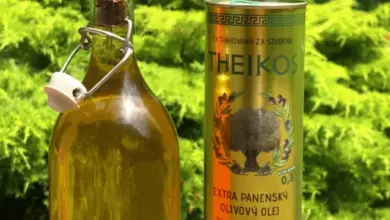 Fľaše extra panenského olivového oleje vedle obalu na venkovní stůl.