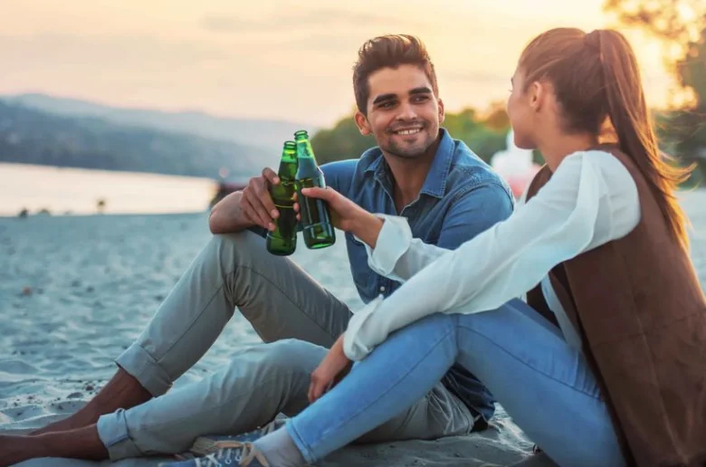 Muž a žena pijí nealkoholické pivo na pláži.