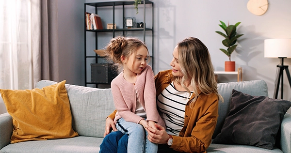 Mother and daughter talking on sofa