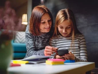 Žena s dcerou se dívá na tablet v interiéru