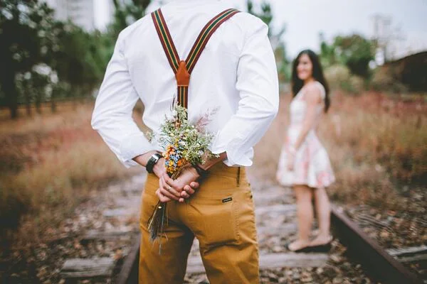 Couple with bouquet behind back