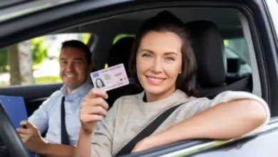 Žena drží řidičský průkaz v autě s instruktorem.