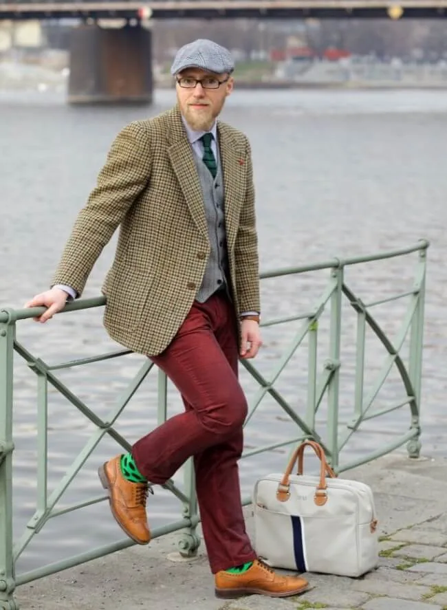 Muž v typickém stylu hipstera stojí u řeky.