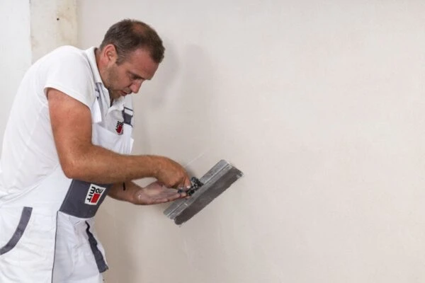 Man applying plaster to wall