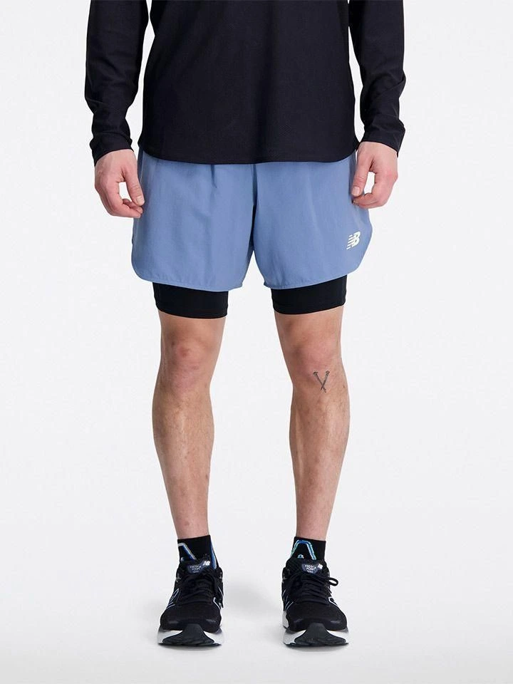 Muž v modrých sportovních kraťasech s logem New Balance.