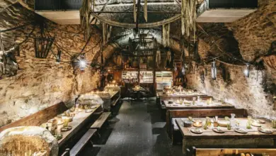Interiér restaurace v jeskyni s dřevěnými stoly pro oslavy.