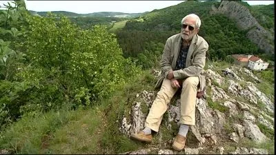 Starosta sedí na skále v přírodě s myšlenkami o řešení konfliktů.