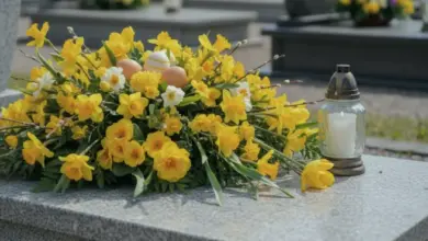 Žluté narcisy s vajíčky a svíčkou na hrobě.