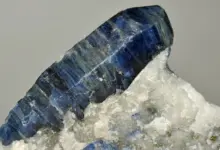Modrý safírový krystal na bílém hornině v přírodním prostředí.