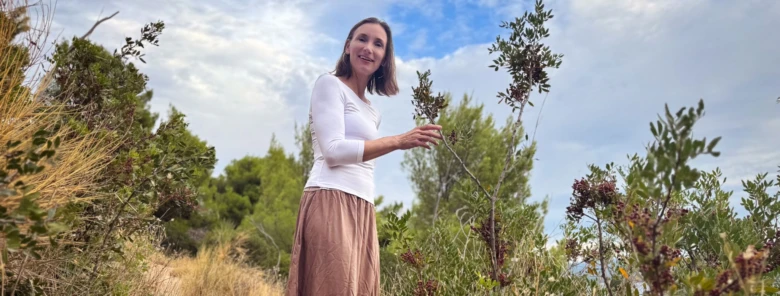 Žena drží větev stromu venku v přírodě.