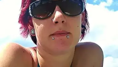 Žena s kroužkem v nosu na pozadí modré oblohy.