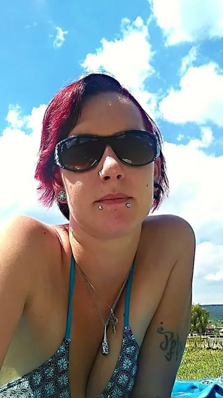 Žena s kroužkem v nosu na pozadí modré oblohy.